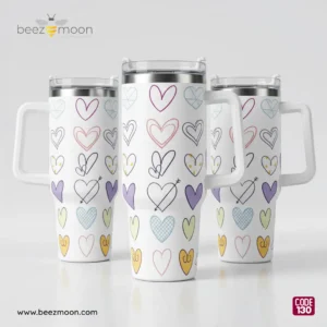 Professional product shot of a Beezmoon white insulated tumbler with multi-colored hand-drawn heart doodles, featuring a white ergonomic handle and clear lid (Code 130).