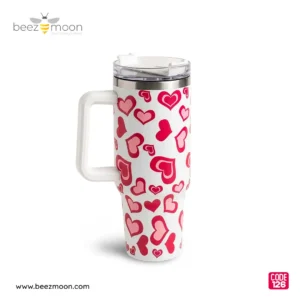 Large white 'Stanley-style' insulated tumbler with a dense, all-over pattern of varied red and pink hearts, a sturdy white ergonomic handle, and a clear flip-straw lid, isolated on a light background. Features "Big size" and "Heavy Duty" build.