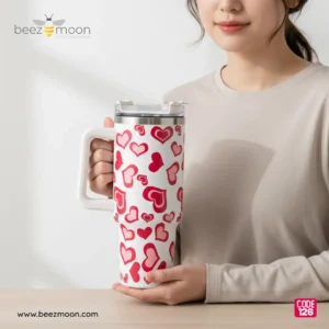 Large white 'Stanley-style' insulated tumbler with a dense, all-over pattern of varied red and pink hearts, a sturdy white ergonomic handle, and a clear flip-straw lid, isolated on a light background. Features "Big size" and "Heavy Duty" build.