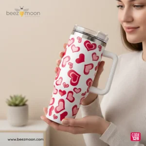 Large white 'Stanley-style' insulated tumbler with a dense, all-over pattern of varied red and pink hearts, a sturdy white ergonomic handle, and a clear flip-straw lid, isolated on a light background. Features "Big size" and "Heavy Duty" build.
